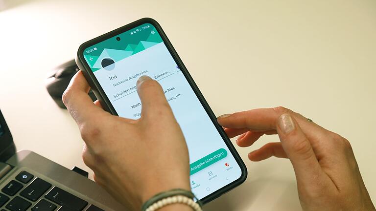 Frau benutzt Handy mit Splitwise-App       -  Zettelwirtschaft und Taschenrechner kann man sich sparen: In der App &bdquo;Splitwise&rdquo; lassen sich gemeinsame Ausgaben unkompliziert erfassen und aufteilen.