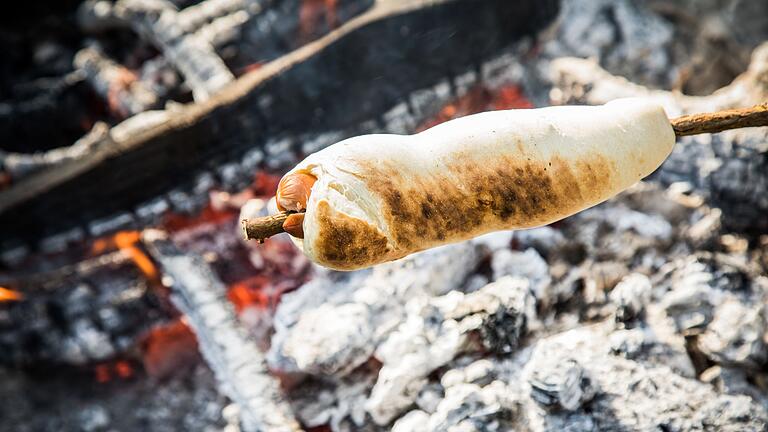 Stockbrot mit Wüstchen im Teig als Hot Dog       -  Wenn der Teig nicht allein um den Knüppel, sondern auch mit um ein Würstchen gewickelt wird, wird aus dem Stockbrot ein Hotdog.