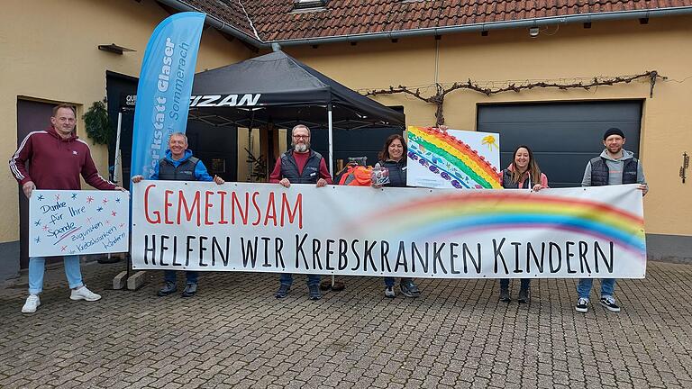 Das Team der SkiWerkstatt Glaser 'Waxlpeter' präsentiert neben dem Banner 'Gemeinsam helfen wir krebskranken Kindern' auch das Regenbogenplakat, das die Kinder des Kindergartens Gaibach gemalt haben. Im Bild (von links)&nbsp; Otto Elmauer (Station Regenbogen), Peter Glaser, Norbert Glaser, Sabine Glaser, Marina Mengler und Tobias Bergner von der SkiWerkstatt Glaser 'Waxpleter'.