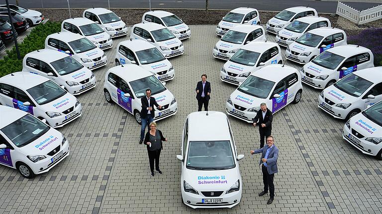 Sie präsentieren die neuen E-Autos der Diakonie Schweinfurt (im Uhrzeigersinn): Sandra Hager-Crasser (Pflegedienstleitung Kitzingen), Marcus Eisner (Geschäftsführer Schuler + Eisner), Johannes Kuther (Leiter Einkauf und stationäre Altenpflege), Thomas Stefi (Verkaufsleiter für Großkunden und Behörden) und Pfarrer Jochen Keßler-Rosa (Vorstand).