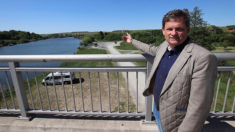Hotel-Investor Ralph Düker deutet mit seiner Hand auf den Standort seines geplanten Hotels an der Volkacher Mainlände. Im Hintergrund am Horizont: Maria im Weingarten. Hotel-Investor Ralph Düker deutet mit seiner Hand auf den Standort seines geplanten Hotels an der Volkacher Mainlände. Im Hintergrund am Horizont: Maria im Weingarten.