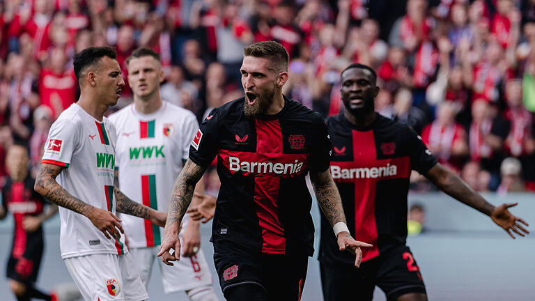 Bayer Leverkusen - FC Augsburg.jpeg       -  Robert Andrich jubelt nach seinem Treffer zum 2:0., die FCA-Spieler Iago und Jeffrey Gouweleeuw wollen gar nicht hinsehen.