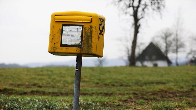 Pressekonferenz zu Post- und Telekommunikationsbranche       -  Ein Briefkasten der Deutschen Post steht auf einer Wiese am Rand einer Siedlung im Bergischen Land (NRW).