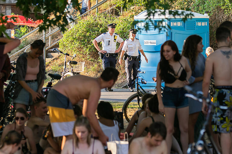 Die Polizei zeigte am Wochenende Präsenz an den Mainwiesen, wie hier am Freitag. Ein Polizeibus kontrollierte am Abend den Radweg, ein Polizeiboot war auf dem Main zu sehen und zwei Polizisten waren zu Fuß unterwegs und wiesen die Leute darauf hin, Abstand zu halten.