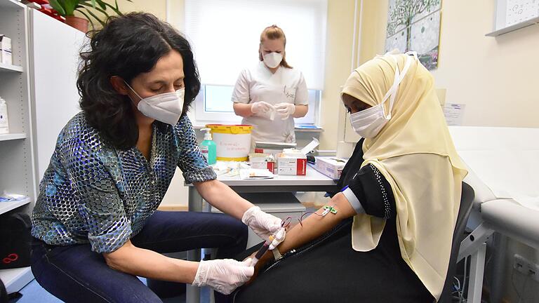 Am Freitag startete im Ankerzentrum bei Schweinfurt eine Corona-Antikörperstudie. Dr. Özlem Anvari nimmt einer jungen Somalierin das Blut ab. Nina Hempel (Mitte), Leiterin des medizinischen Fachpersonals vor Ort, unterstützt die Ärztin.