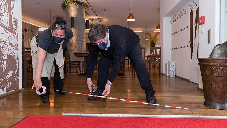 Coronagerecht: Kurt Schubert und Servicekraft Cora Schreck bereiten mit Absperrband und Zollstock den Ratskeller auf die Öffnung an diesem Montag vor.&nbsp;