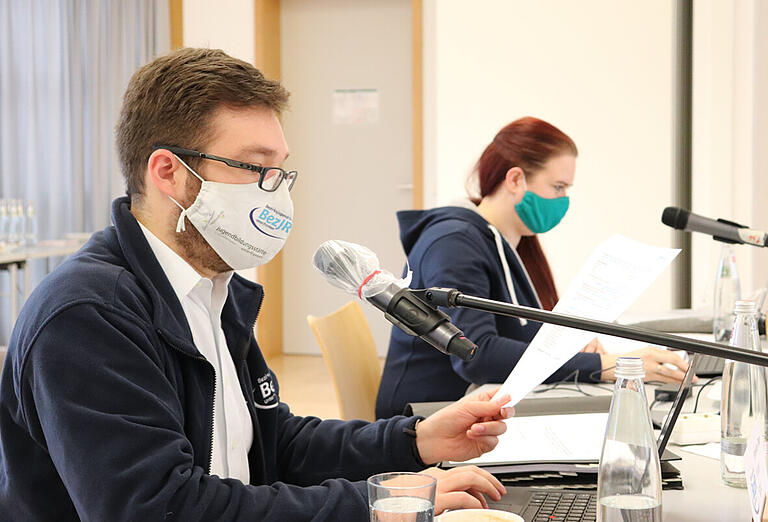 Bezirksjugendringsvorstandsbeisitzer Sebastian Dietz, zugleich Diözesanvorsitzender des Bunds der Deutschen Katholischen Jugend (BDKJ), moderiert die digitale Vollversammlung des Bezirksjugendrings, im Hintergrund ist Bezirksjugendringsvorsitzende Jennifer Wolpensinger.