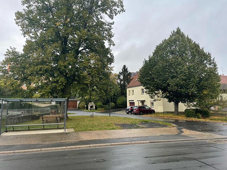 Blick auf den Dorfplatz von Kirchlauter mit der Schulbushaltestelle (links) und der Lauterquelle im Hintergrund, der neu gestaltet werden soll.