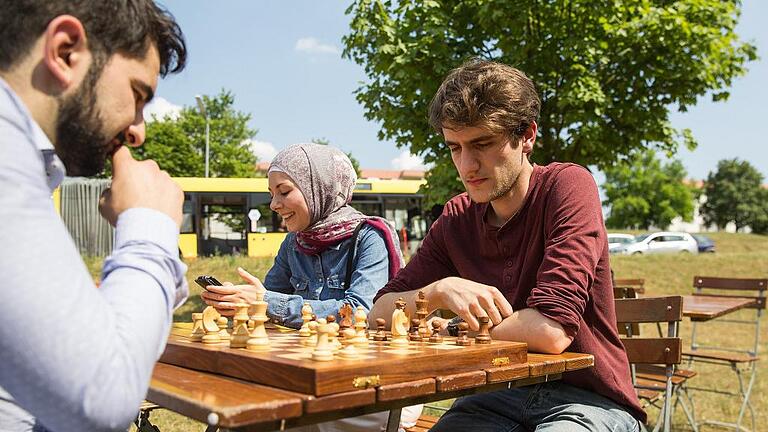 (huGO-ID: 28796013)  Semih (25, blaues Hemd) und Joschka (21, rotes Hemd) spielen Schach.  Studenten treffen Flüchtlinge am Uni-Sprachzentrum.  Gemeinsames Arbeiten zur arabischen Kultur.  Sommerfest und Projekt der Uni mit Flüchtlingen  An diesem Freitag, 12. Juni veranstaltet das Zentrum für Sprachen der Uni (ZFS) am Campus Hubland Nord im Matthias-Lexer-Weg von 14 bis 18 Uhr ein Sommerfest. Es entstand im Rahmen eines Projektes von deutschen Studierenden, die Arabisch als Fremdsprache lernen, und arabischen Flüchtlingen.  Gamiela Safyia, die Leiterin der Arabischabteilung des ZFS, und Hülya Düber, die Sozialreferentin der Stadt, riefen das Projekt ins Leben, um junge Deutsche und arabische Flüchtlinge zusammenzubringen. In Workshops erarbeiteten alle gemeinsam verschiedene Aspekte der arabischen Kultur. Die komplexen Schriftzeichen, Kaffeehauskultur, Lieder und Tänze standen ebenso auf dem &ldquo;Lehrplan&ldquo; wie Spezialitäten der arabischen Küche.  Die Flüchtlinge haben so die Möglichkeit, ihre Kultur darzustellen und die deutsche Sprache zu lernen. Die Studierenden erhalten Informationen zu arabischen Ländern aus erster Hand und können ihre Arabischkenntnisse verbessern.    FOTO:?Patty Varasano nnnnnnn