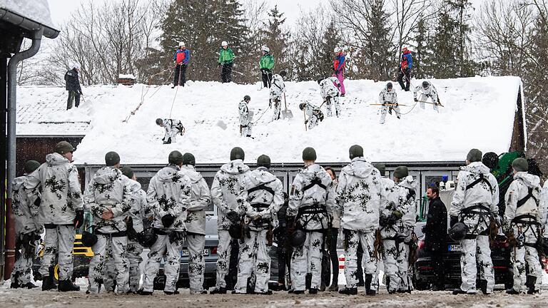 Wie hier in Wolfratshausen sind Helfer von Bundeswehr, Bergwacht, THW und Polizei bemüht, den immer schwerer werdenden Schnee von den Dächern zu bekommen.