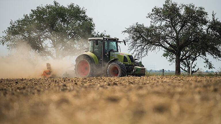 Dürre setzt Landwirtschaft zu       -  Ein Landwirt fährt mit seinem Traktor über ein Feld und zieht eine Staubwolke hinter sich her. Die Bauern haben wegen der Trockenheit Probleme bei Aussaat von Wintergetreide.