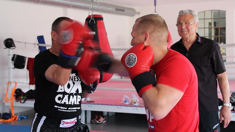 Wilhelm Ciufrida (im Hintergrund) aus Gemünden hat das Fitnessboxen &bdquo;CiuPunch&ldquo; erfunden. Hier demonstrieren es im Boxcamp Lohr Inhaber Sven Amend (rot), der mit Andreas Kuhn eine Trainingseinheit absolviert.