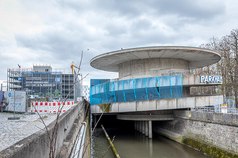 Das alte Quellenbachparkhaus über der Pleichach, eine Lage, die den Abriss nicht erleichtert. Links im Hintergrund der Neubau.