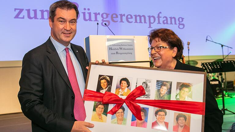 Ministerpräsident Markus Söder überreicht Barbara Stamm einen Bilderrahmen mit Autogrammkarten aus mehr als vier Jahrzehnten Politik.