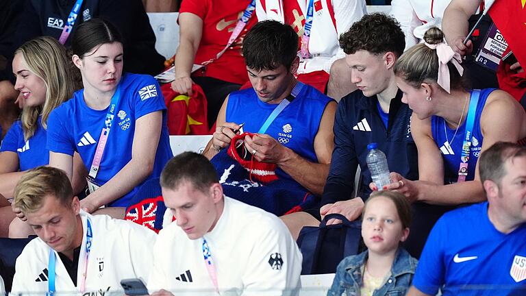 Paris 2024 - Wasserspringen       -  Tom Daley strickt während eines Olympia-Wettkampfs auf der Tribüne.
