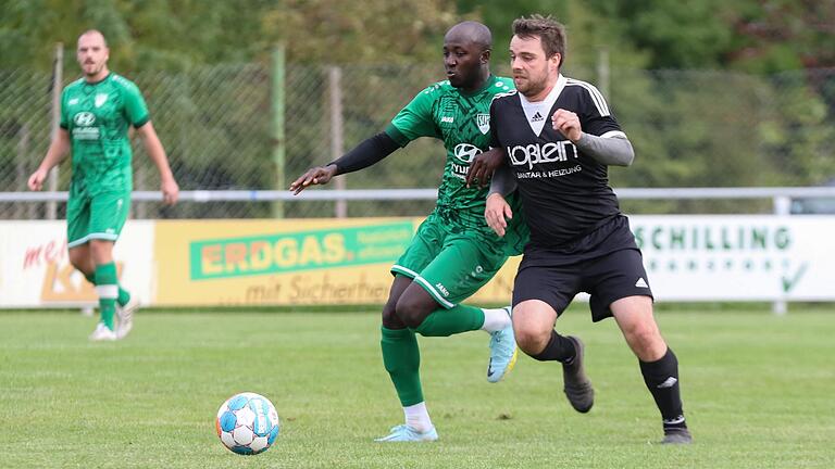 Sita Diaby (links) vom SV Heidingsfeld im Laufduell mit Andreas Herrmann von der SG Buchbrunn-Mainstockheim. Die SG gewann ihr Heimspiel gegen Heidingsfeld in der letzten Spielminute durch ein kurioses Tor.