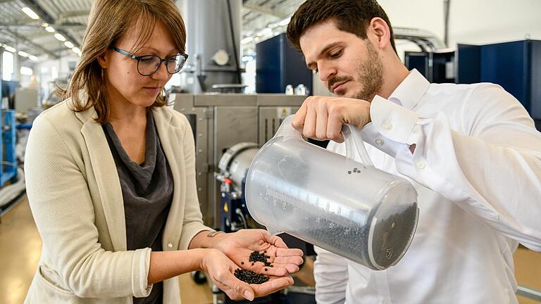 Mit Hilfe einer modernen Maschine (Hintergrund) erforschen Marieluise Lang und Lars Helmlinger am Süddeutschen Kunststoffzentrum in Würzburg, wie Plastikmüll besser wiederverwertet werden kann. Das schwarze Kunststoffgranulat steht dabei im Mittelpunkt. Mit Hilfe einer modernen Maschine (Hintergrund) erforschen Marieluise Lang und Lars Helmlinger am Süddeutschen Kunststoffzentrum in Würzburg, wie Plastikmüll besser wiederverwertet werden kann. Das schwarze Kunststoffgranulat steht dabei im Mittelpunkt.