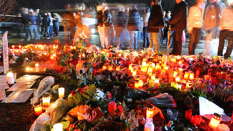 Trauernde Schüler und Einwohner des Ortes Winnenden stehen am 12. März 2009 nahe der Albertville-Realschule (im Hintergrund) vor zahllosen Blumen und Grablichtern.