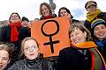 Weltfrauentag       -  Zum Weltfrauentag versammeln sich am Dienstag (08.03.2005) auf dem Alexanderplatz in Berlin Frauen und Mädchen am Rande einer Kundgebung rund um ein Schild mit dem Frauenzeichen. Der Internationale Frauentag ist seit 1921 auf den 8. März festgelegt.