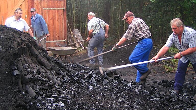 Holzkohlenernte in Glasofen im Landkreis Main-Spessart. Nach einer Woche kann der Meiler geöffnet und die Holzkohle entnommen werden. Sie findet in der Region reißenden Absatz.
