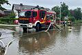 Einsatzkräfte der Feuerwehr Gerolzhofen pumpen am Sonntagvormittag Wasser von einer überfluteten Straßenkreuzung in Mering im Landkreis Aichach-Friedberg.