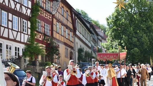 Katholiken feiern Fronleichnam       -  Vielerorten im Heimatkreis haben die Katholiken an Fronleichnam ihren Glauben bekundet. Unser Beispielbild stammt aus der Stadt Königsberg. Die ist zwar Grund ihrer einstigen Zugehörigkeit zum Herzogtum Sachsen-Coburg-Gotha überwiegend protestantisch geprägt. Doch seit Jahrzehnten gibt hier auch die katholische Pfarrgemeinde Sankt Josef. Diese hielt am Fronleichnamstag, dem &bdquo;Hochfest des Leibes und Blutes Christi&ldquo;, eine feierliche Heilige Messe mit anschließender Prozession ab. Der Name &bdquo;Fronleichnam&ldquo; stammt von &bdquo;fron&ldquo;, &bdquo;Herr&ldquo; und &bdquo;lichnam&ldquo;, &bdquo;Leib&ldquo;, und weist auf die Elemente der Eucharistie hin. Seine Beliebtheit bei den katholischen Mitbürgern verdankt dieser Festtag vor allem der Prozession, bei der die Elemente der Eucharistie durch die Straßen getragen werden. In Königsberg trug Kaplan Michel Schmitt die &bdquo;Monstranz&ldquo;, die die Hostien beinhaltet, durch die Straßen der Altstadt, gefolgt von den Gläubigen. An herrlich mit Blumen geschmückten Stationen wurden die Fürbitten gebetet und gab der Geistliche seinen Segen. Angeführt wurde die Prozession von der Blaskapelle aus Prappach.