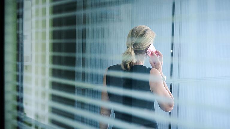 Frau steht im Büro und telefoniert       -  Beim Telefonieren aufstehen und umhergehen - das entlastet den Rücken.