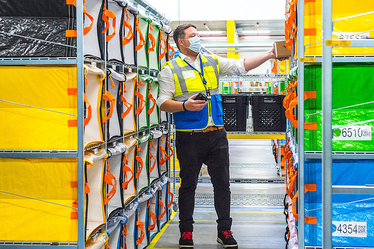 In solche farbigen Taschen werden die Pakete verteilt, wie Manager Thorsten Freers hier zeigt. Die Farben sollen den Zustellerinnen und Zustellern das Auffinden des benötigten Pakets erleichtern.