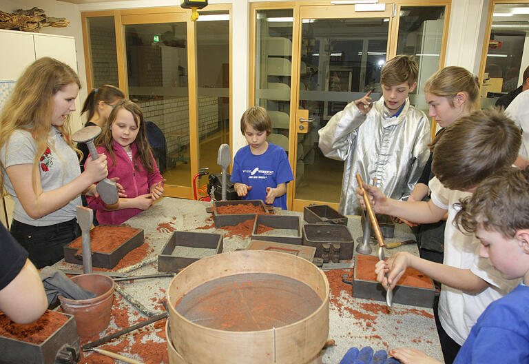 Sand in Gussformen verdichten, eine Arbeit der sich auch jüngere Schüler hingeben können.