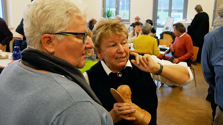 Reinhilde Prinz vom Geschichtsverein VKM in Mühlhausen (Bildmitte) beim Erklären der Ausstellungsgegenstände. In der Hand hat sie eine Holzfigur, die Valentin Kraus in seinen ersten Künstlerjahren schnitzte.