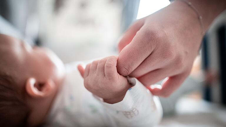 Geburtenrate.jpeg       -  Ein Baby klammert sich an den Finger seiner Mutter.