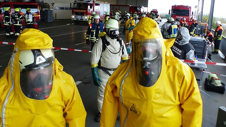 Großübung im Knauf-Logistikzentrum: Das Szenario geht von einem Gefahrgut-Unfall aus. Vorsichtig nähern sich Feuerwehrleute in gelben Schutzanzügen dem Einsatzort.