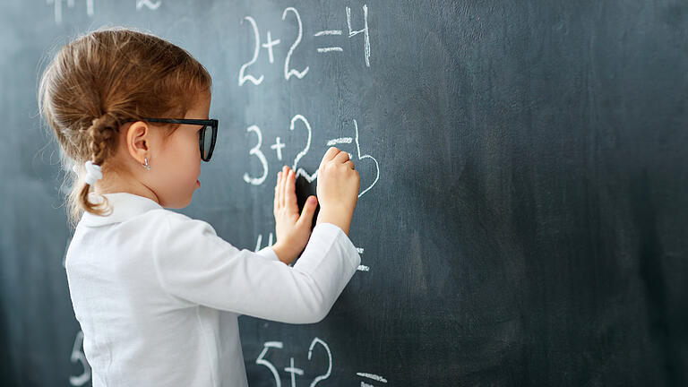 Happy schoolgirl preschool girl with book near school blackboard       -  Symbolbild: Schulkind an der Tafel