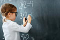 Happy schoolgirl preschool girl with book near school blackboard       -  Symbolbild: Schulkind an der Tafel