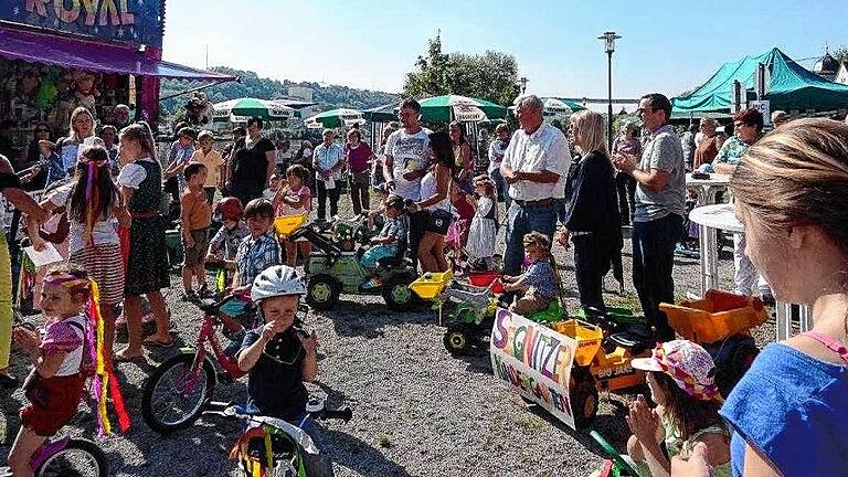 Kirchweihumzug der Segnitzer Mainräuber       -  (nb)   Einen Kirchweihumzug der besonderen Art gab es am Sonntag in Segnitz. Die Kinder des Kindergartens, die Segnitzer Mainräuber, machten sich mit Tretautos, Traktoren und Rollern auf, um an den Rummelplatz am Main zu ziehen. Unterwegs holten sie Pfarrer Matthias Wagner an der Kirche und die zweite Bürgermeisterin Marlene Bauer am Rathaus ab. Beide, Pfarrer und Bürgermeisterin, wurden jeweils mit Liedern aus Kinderkehlen empfangen. Dafür gab es dann Süßigkeiten und Kirchweifreikarten zur Belohnung. Am Festplatz wartete dann nicht nur das Karussell auf die Kinder, für die Erwachsenen gab es zugunsten des Kindergartens Kaffee, Kuchen, Speisen und Getränke.