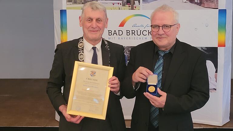 Pfarrer Gerd Kirchner hat die Stadtplakette in Gold von Bad Brückenau bekommen       -  Gerd Kirchner (rechts) gemeinsam mit dem amtierenden Bürgermeister Jürgen Pfister und der Stadtplakette in Gold samt Ehrenurkunde.