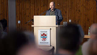 Infoveranstaltung in Himmelstadt zur geplanten Geflüchtetenunterkunft       -  Bürgermeister Herbert Hemmelmann eröffnet den Abend und richtet die ersten Worte an die geschätzt gut 300 Besucherinnen und Besucher. Rund 300 Menschen besuchen am 07.04.25 die Informationsveranstaltung in der Mehrzweckhalle in Himmelstadt zur geplanten und umstrittenen Unterkunft für Geflüchtete. Zum Diskussionsabend wurden auch Vertreter der Politik, der Regierung und der Polizei geladen.