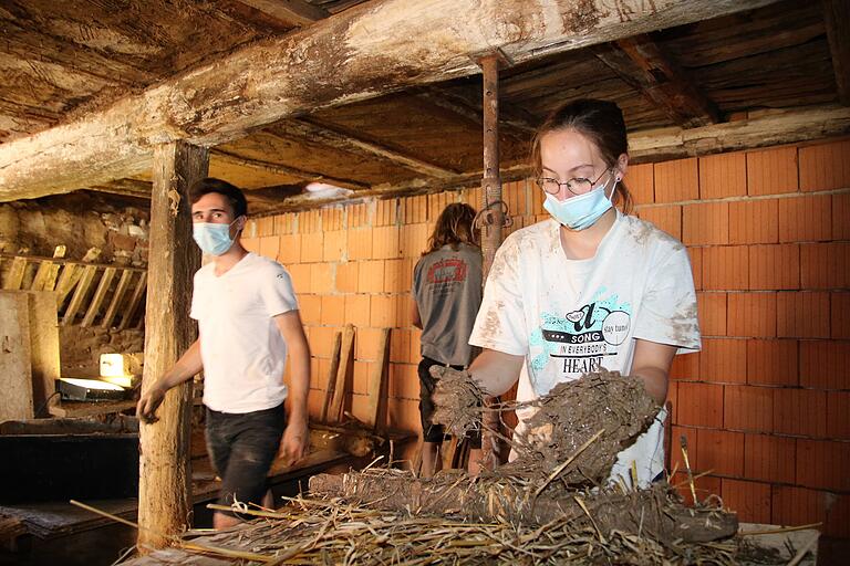 Im kühlen Stall des Riehlshofs knetet die 19-jährige Katrin Betz aus Nürnberg einen Lehmwickel für die Holzbalken zusammen.