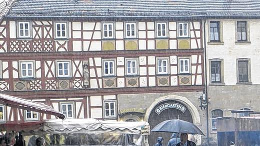Regenmantel gefällig? - (bw) Den Titel „Regenmantelsonntag“ hätte der „Mantelsonntag“ in Hofheim zeitweilig besser getroffen: Das Herbstwetter zeigte sich mit Regenschauern und stürmischen Böen von seiner unbequemen und nicht verkaufsfördernden Seite. Wer vor dem starken Regenschauer bereits durch die Hofheimer Innenstadt bummelte und nicht gut beschirmt war, suchte Schutz unter den Dachüberständen und in den Geschäften, um in aller Ruhe nach Schnäppchen Ausschau zu halten. Die Marktbeschicker entlang den Straßen und auf dem Marktplatz waren gut gerüstet, deckten ihre Waren mit Planen ab. Und Obstverkäufer Reinhold Dotzel aus Lindach hielt bei den starken Windböen den schützenden Schirm fest. Regenmantel gefällig? - (bw) Den Titel „Regenmantelsonntag“ hätte der „Mantelsonntag“ in Hofheim zeitweilig besser getroffen: Das Herbstwetter zeigte sich mit Regenschauern und stürmischen Böen von seiner unbequemen und nicht verkaufsfördernden Seite. Wer vor dem starken Regenschauer bereits durch die Hofheimer Innenstadt bummelte und nicht gut beschirmt war, suchte Schutz unter den Dachüberständen und in den Geschäften, um in aller Ruhe nach Schnäppchen Ausschau zu halten. Die Marktbeschicker entlang den Straßen und auf dem Marktplatz waren gut gerüstet, deckten ihre Waren mit Planen ab. Und Obstverkäufer Reinhold Dotzel aus Lindach hielt bei den starken Windböen den schützenden Schirm fest.