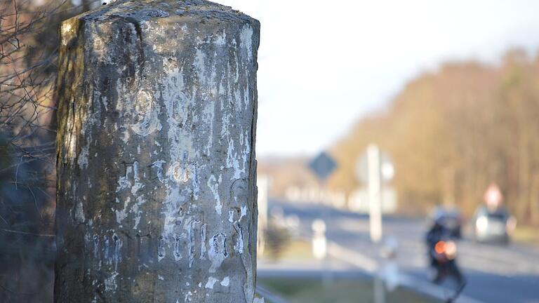 Die Schrift auf dem Kilometerstein unweit der 'Schwarzen Pfütze' ist verwittert: Nach Poppenhausen sind es noch 8,5 Kilometer und nach Münnerstadt 9 Kilometer, stand hier früher zu lesen.