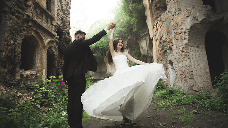 Beautiful romantic wedding couple of newlyweds hugging near old castle       -  Mittelalter trifft auf Moderne: Eine Boho-Hochzeit auf einer Burg hat seinen ganz besonderen Charme.