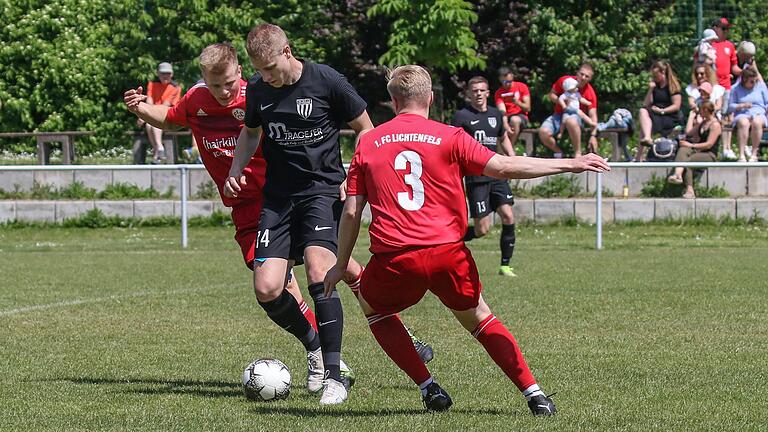 Mathis Böhler (Mitte) vom TSV Rottendorf hält den Ball gegen Leon Holzheid (hinten) und Christoph Mohr vom FC Lichtenfels.