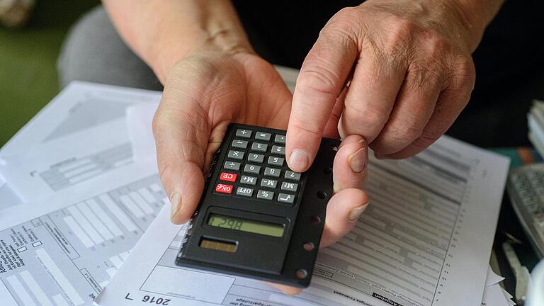 Ein Rentner tippt angesichts der fälligen Steuererklärung in seinen Taschenrechner. Besonders für Senioren ist das Ausfüllen der Steuerformulare oft eine Herausforderung.