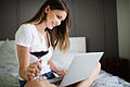 Happy woman using a laptop searching online on the bed at home       -  Videochats machen es möglich: Trotz Corona müssen angehende Bräute nicht auf ihren Junggesellenabschied verzichten.