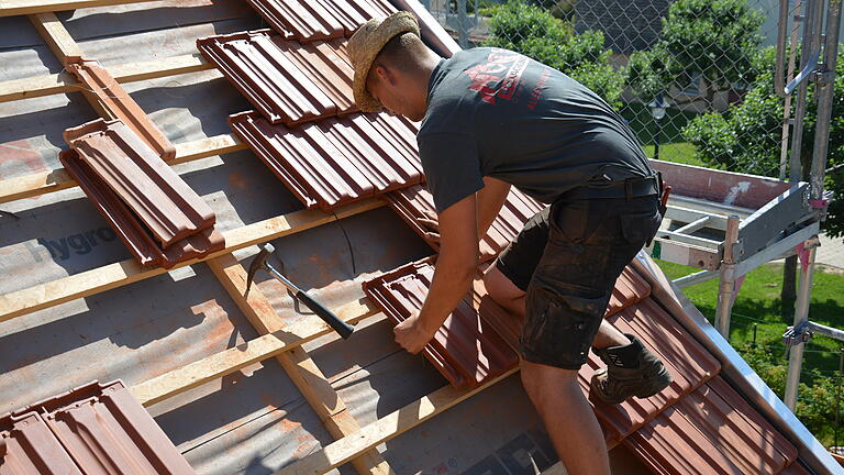 Ziegel für Ziegel platziert der Dachdecker auf dem Dach – so er welche hat (Archivbild).