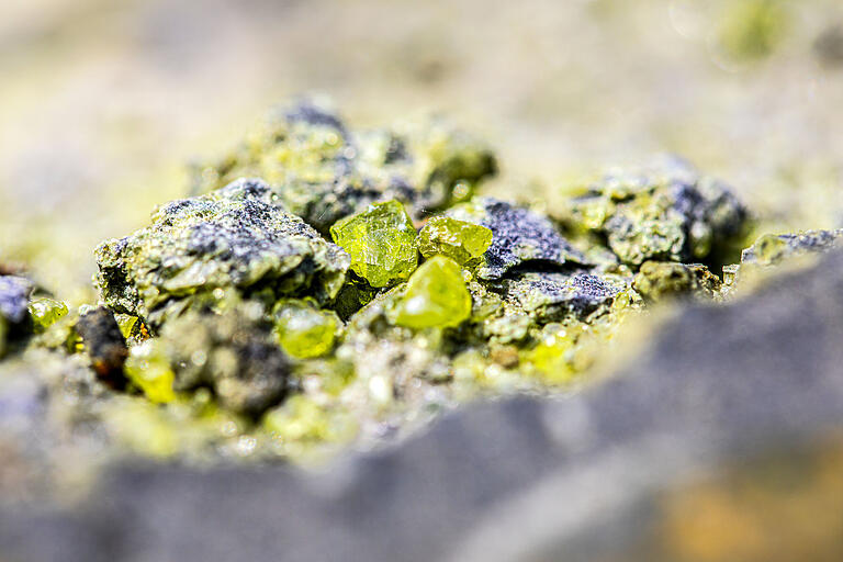 Grüner Olivin: Schön für das Auge, ein Entzücken für Mineralienfreunde, aber eher lästig für den Steinbruchbetreiber: Der Basalt vom Zeilberg enthält viele Drusen mit dem Silikatmineral. Grüner Olivin: Schön für das Auge, ein Entzücken für Mineralienfreunde, aber eher lästig für den Steinbruchbetreiber: Der Basalt vom Zeilberg enthält viele Drusen mit dem Silikatmineral.