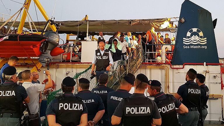 Seenotrettung im Mittelmeer       -  Migranten gehen von Bord des Rettungsschiffs &bdquo;Sea-Watch 3&ldquo; im Hafen der Insel Lampedusa.