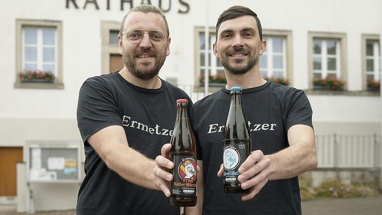 Die Ermetzer, hier Andreas Engmann und Patrick Rädlein (rechts), haben zum 975-jährigen Bestehen Ermershausens ein Festbier (linke Flasche) kreiert. Ihr erstes war das 'Rebell Hell' (rechte Flasche).