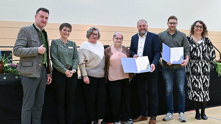 Christoph Bullinger (2. von rechts) freut sich über die 12.000. Ehrenamtskarte im Landkreis Würzburg. Annelore Kunert (Mitte) erhielt von Landrat Thomas Eberth (3. von rechts) die 12.002. Ehrenamtskarte in der Gold-Version. Eibelstadts Bürgermeister Markus Schenk (links), Sabine Wendel von der Servicestelle Ehrenamt (2. von links), Sieglinde Krieger (3. von links) von der Rheumaliga Ochsenfurt und Kerstin Gressel, Ehrenamtsbeauftragte des Landkreises Würzburg (rechts), würdigten das jahrelange Engagement der Geehrten.&nbsp;