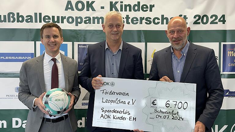 Die AOK-Sponsorenwand mit den Firmen, die gespendet haben sowie (von links) Beiratsvorsitzender der Arbeitgeber Christoph Höger, AOK-Direktor Frank Dünisch und Vorsitzender des Fördervereines Leopoldina e.V. Stefan Stapf.